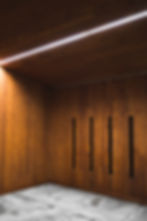 Wooden theatre entrance door, with natural knots wood panels and vertical slits, creating a warm ambiance.