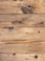 Wooden planks with distinct grain patterns and knots. Light brown tones create a rustic texture.